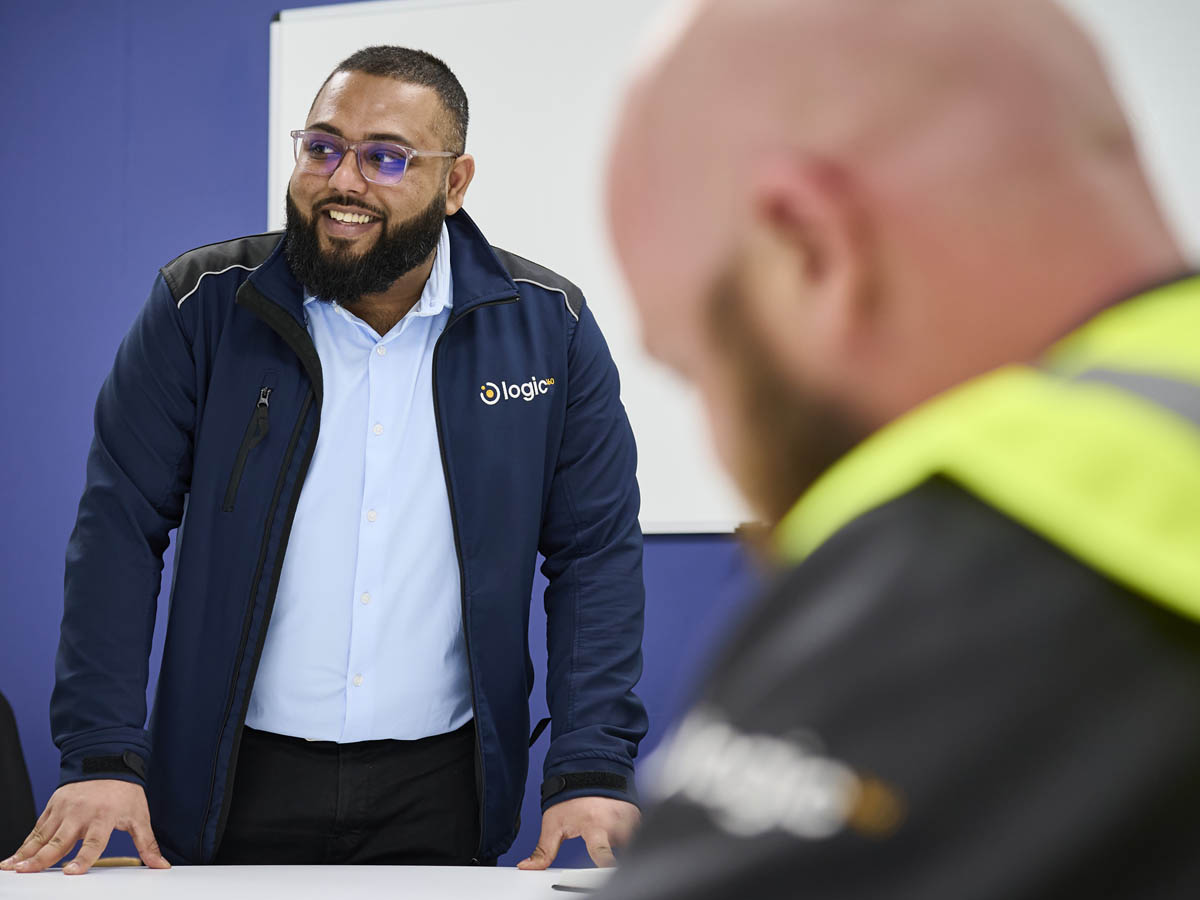 A Logic 360 consultant in branded uniform briefing a worker in a hi-vis vest during onboarding