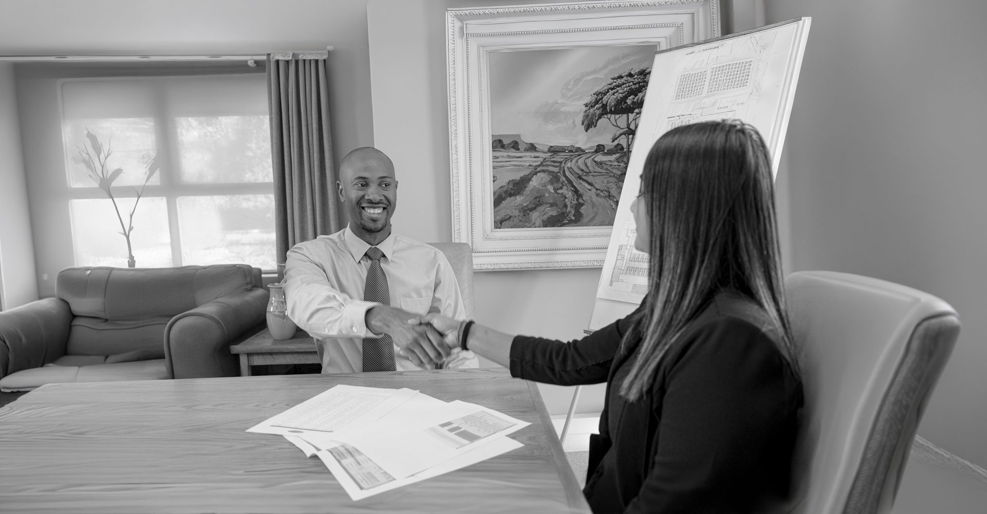 A handshake across a desk at the end of an interview