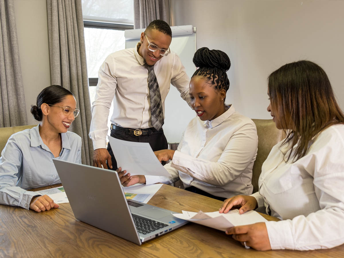 A South African team reviewing workforce documents around a laptop in an office meeting